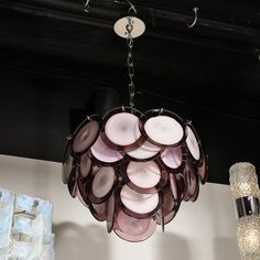 This refined modernist chandelier was realized in Murano, Italy- the island off the coast of Venice renowned for centuries for its superlative glass production. It features a conical body composed of a wealth of handblown Murano circular shades with opaque centers and translucent surrounds in a rich amethyst hue. The chandelier attaches to the ceiling via a lustrous chrome chain and a conical canopy that formally reiterates the curvilinear forms expressed elsewhere in the chandelier. With its un Curvilinear Forms, Disc Chandelier, Murano Italy, The Coast, Murano Glass, Century Modern, Color Pop, Amethyst, Mid Century