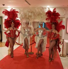 three women in red and white costumes standing on a red carpet