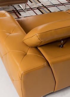 a brown leather couch sitting on top of a white floor next to a wooden table