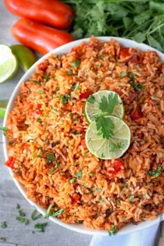 mexican rice with cilantro and lime in a white bowl on a table next to tomatoes