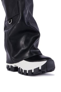 The AZALEA WANG Ezrah Black Boot is a flatform sneaker boot hybrid featuring a faux leather upper, a fold-over knee-high shaft, a belted design, and a slightly covered platform rubber lug sole. Complete with functional cargo side pockets, a pull-on fit, and silver metallic hardware accents. (all measurements approximate from a size 7.5) - DenimTextile Upper - Square Toe - Flatform Wedge Sole - 16” Shaft Height - 19” Shaft Opening Circumference - 13” Calf Circumference  - 2.25” Flatform Sole Height - 3” Chunky Heel Height - Imported Product ID: 387462 Flatform Sneakers, Azalea Wang, Lug Sole, Chunky Heel, Chunky Heels, Black Boots, Knee High, Metallic Silver, Sneaker Boots