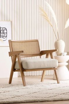 a wooden chair sitting on top of a rug next to a vase