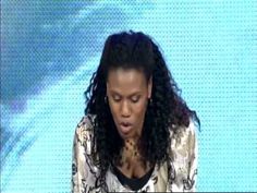 a woman with long hair sitting at a table in front of a tv screen and making a face