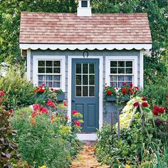 a small garden shed with flowers around it