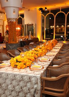 a long table is set with yellow flowers and place settings for an elegant dinner party