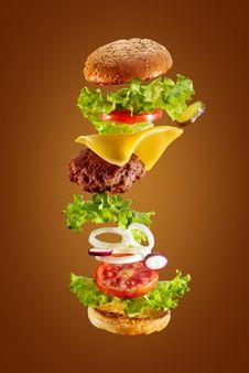 a hamburger flying through the air with lettuce, tomato and cheese on it