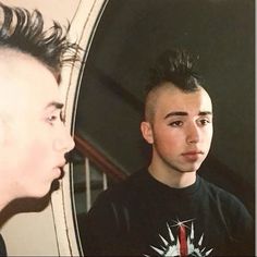 a man looking at himself in the mirror with his hair combed back and undercut