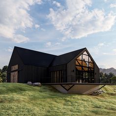 a large black house sitting on top of a lush green field under a blue sky