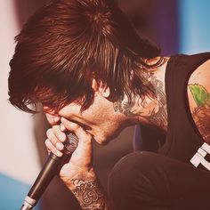 a man with tattoos on his arm holding a microphone