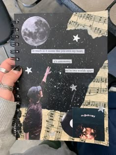 someone is holding up a book with pictures and words on it, in front of the moon