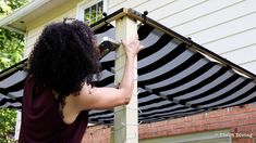 a woman is fixing an awning outside