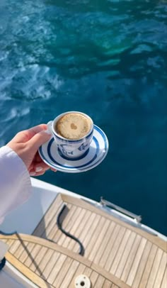 a person holding a cup of coffee on top of a boat