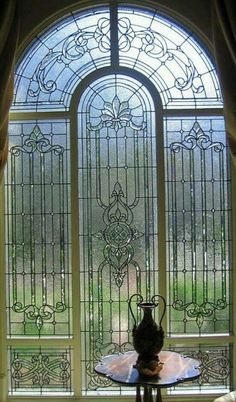 a table with a vase on it sitting in front of a large stained glass window