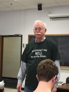 an older man standing in front of a blackboard wearing a t - shirt that says, everything i say will be on the exam