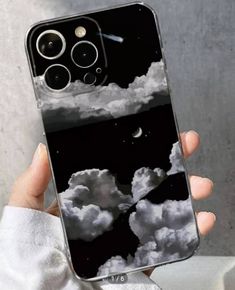 a person holding up a phone case with clouds in the sky and moon on it