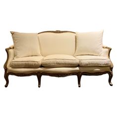 an old fashioned couch with white pillows on it's back and armrests