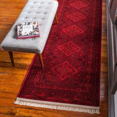 a red rug is on the floor next to a white bench with a magazine in it