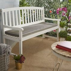 a white bench sitting on top of a wooden floor next to a potted plant