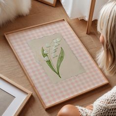 a woman sitting on the floor looking at a painting with flowers in front of her