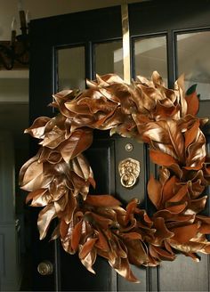 a wreath is hanging on the front door with gold foil leaves and a lion's head