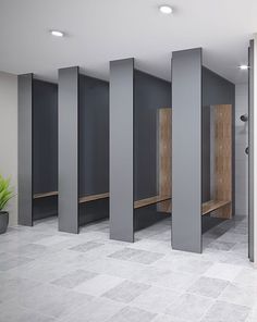 an empty public restroom with black stalls and white tile flooring, surrounded by planters