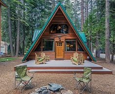 a small cabin in the woods with two lawn chairs and a fire pit underneath it