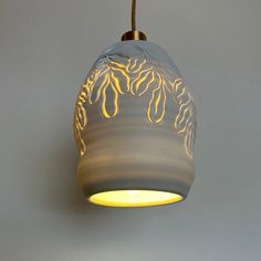 a light hanging from a ceiling with a white and yellow design on it's side