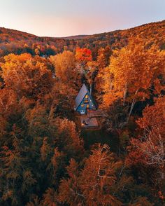 an aerial view of a house surrounded by trees in the fall with leaves turning colors