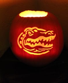 a pumpkin carved to look like an alligator's head is lit up in the dark