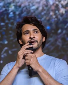 a man holding a microphone while standing in front of a crowd