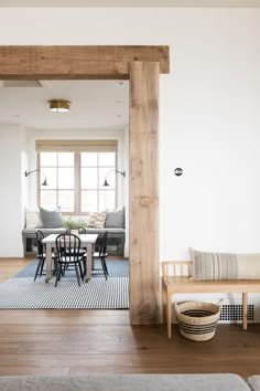 an open living room and dining area with wood flooring, white walls and wooden beams