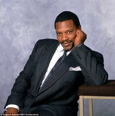 a man in a suit and tie sitting on a chair with his hand to his ear