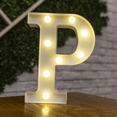 the letter p is lit up with lights and sits on top of a wooden table