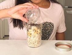 a woman is pouring something into a jar