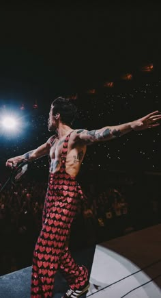 a man with tattoos on his arms and chest is performing in front of an audience