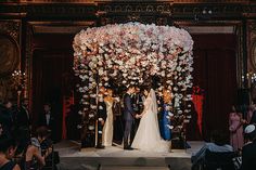 the bride and groom are getting married in front of an elaborate floral arch at their wedding ceremony