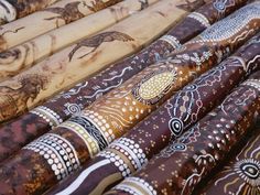 many different types of umbrellas lined up on a table with wood sticks in the background