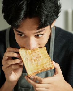 a young man is biting into a piece of bread