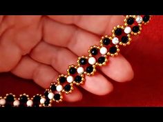 a woman's hand holding a black and white beaded bracelet with pearls on it