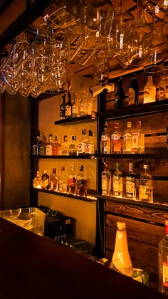 a bar with many bottles and glasses on the shelves in front of glass chandeliers