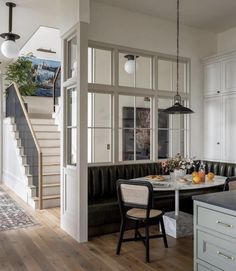 a kitchen and dining area with white walls, wood floors and black leather couches