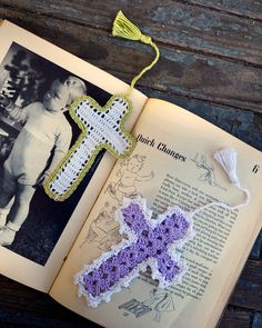 an open book with a crocheted cross hanging from it