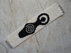 a black and white beaded bookmark with an image of a spiral on it