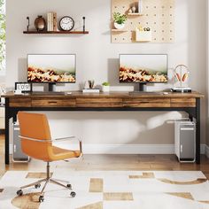 two computer screens sitting on top of a wooden desk