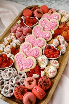 a wooden tray filled with lots of heart shaped cookies