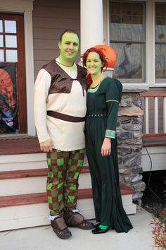 a man and woman in costume standing on the front steps of a house with their faces painted green