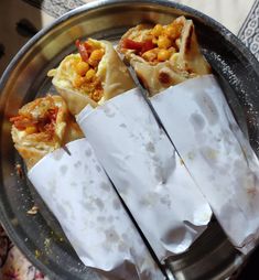 three pieces of food sitting on top of a metal pan with napkins wrapped around it