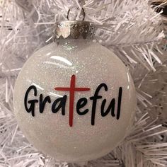 a white ornament with the word grateful on it hanging from a christmas tree