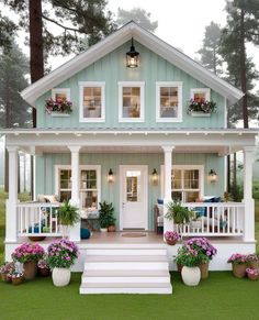 a small blue and white house with flowers on the porch