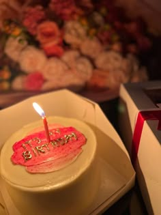 a birthday cake sitting on top of a white plate with a lit candle in it